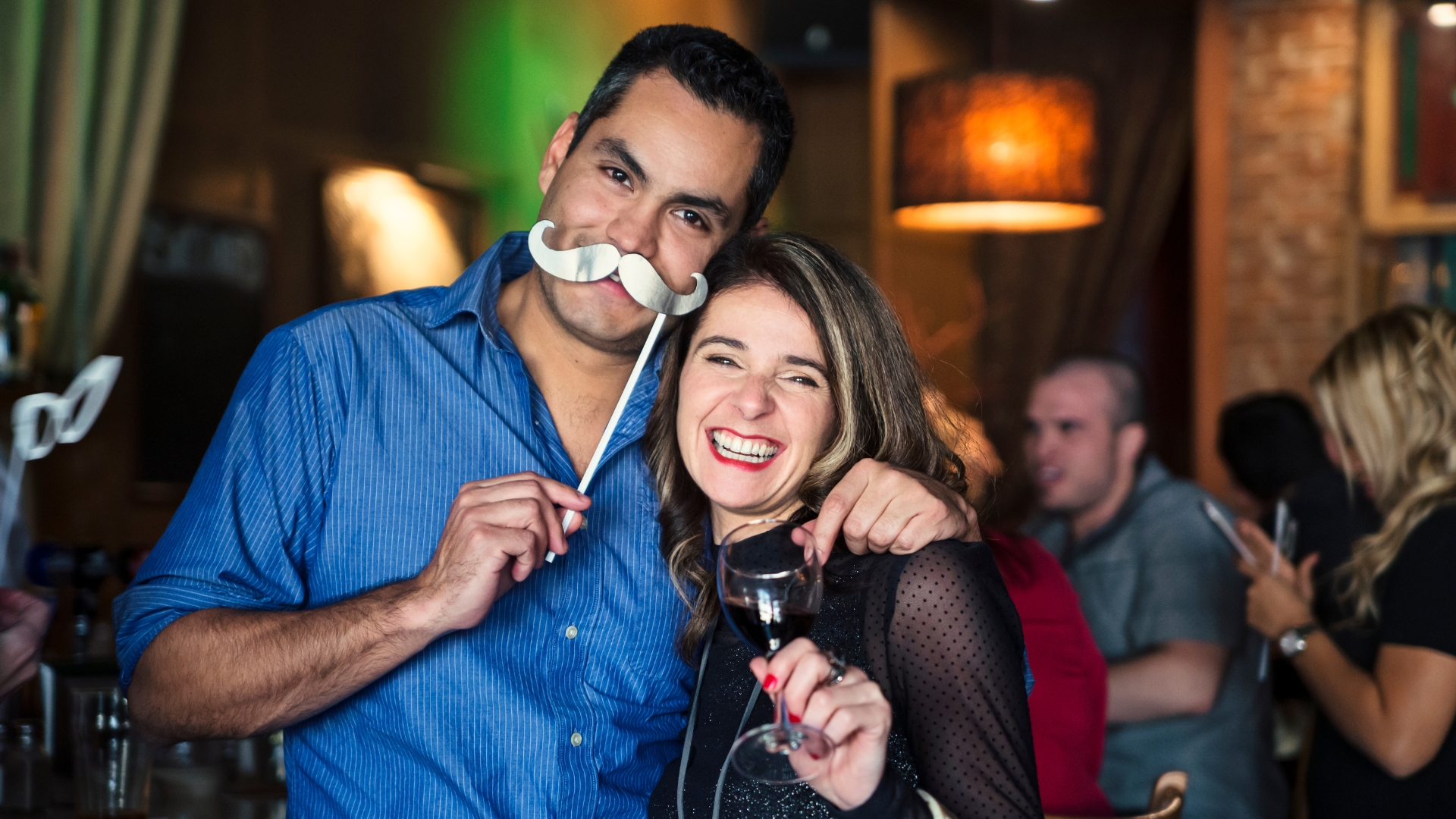 Deux personnes souriantes avec un accessoire moustache.