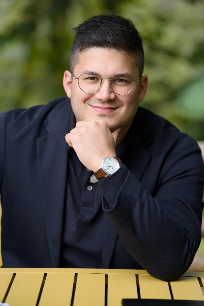 Homme souriant portant lunettes et montre-bracelet.