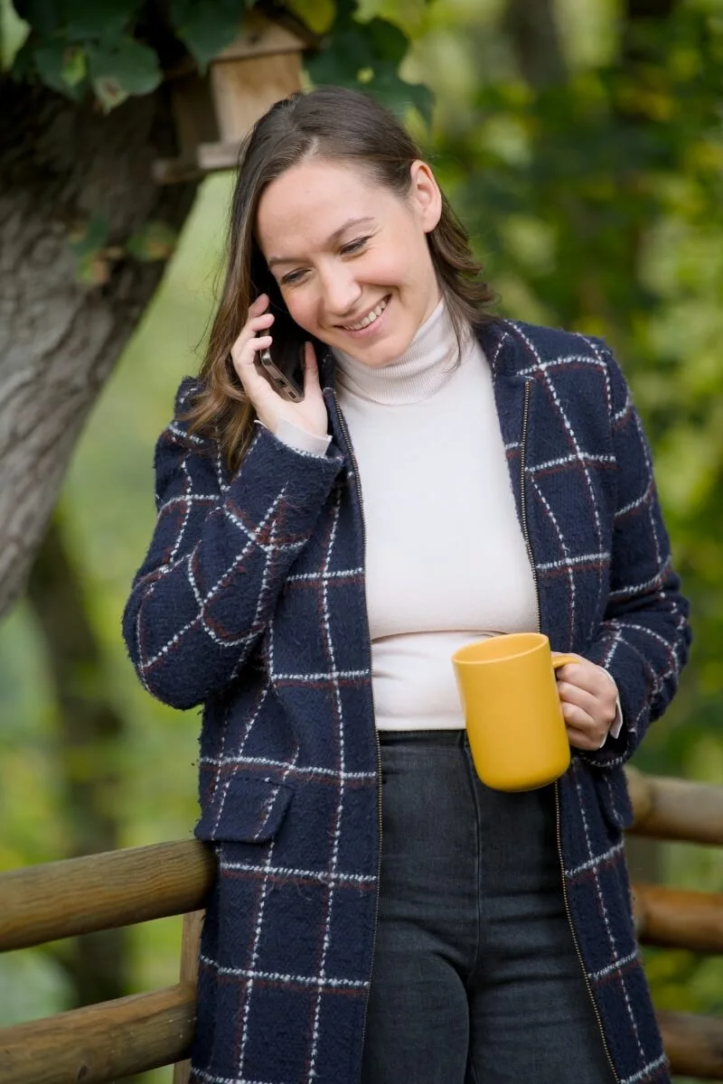 Femme souriante au téléphone avec tasse jaune.