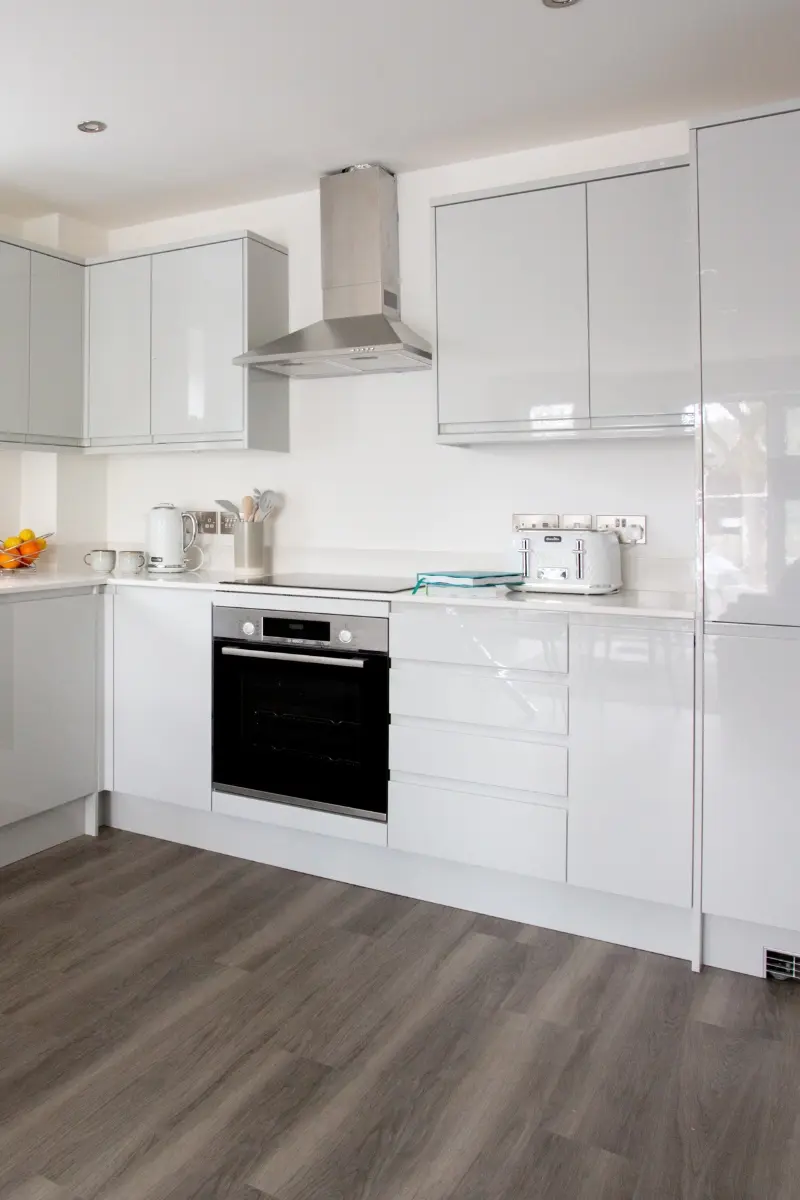 photo-cuisine-blanche-moderne-immobilier-interieur Cuisine moderne avec électroménagers et plan de travail.