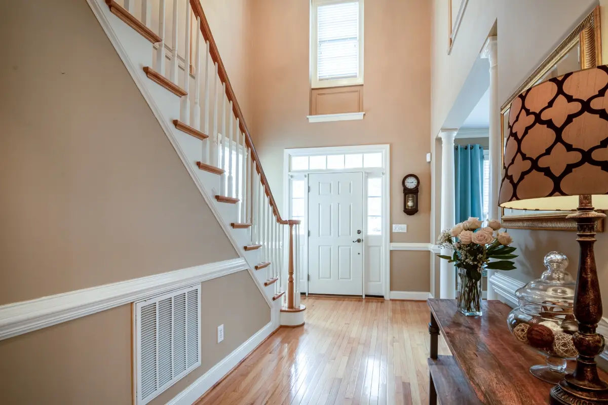 photo-entree-maison-chaleureuse-immobilier Entrée lumineuse avec escalier et décoration élégante.