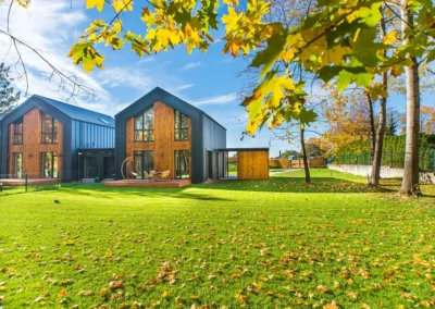 Maison moderne en bois avec grand jardin verdoyant.